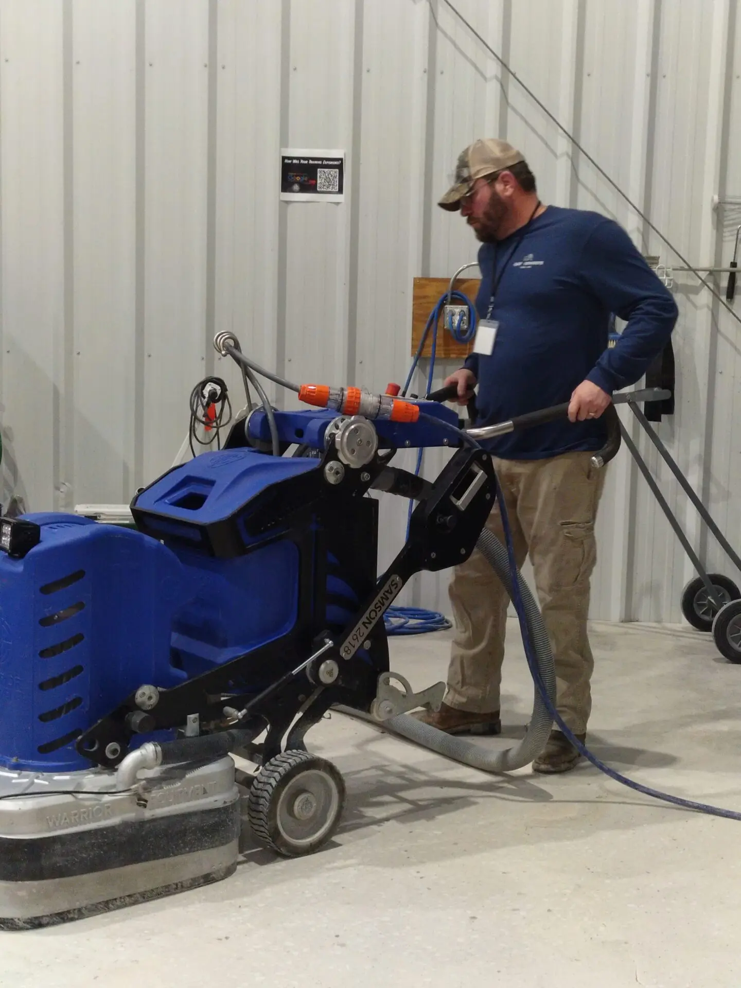 Man operating large blue floor machine.