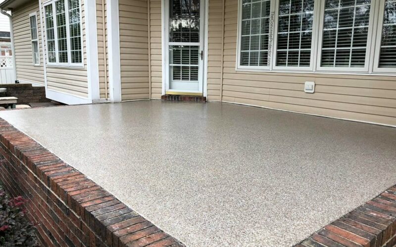 Concrete patio with brick border and windows.