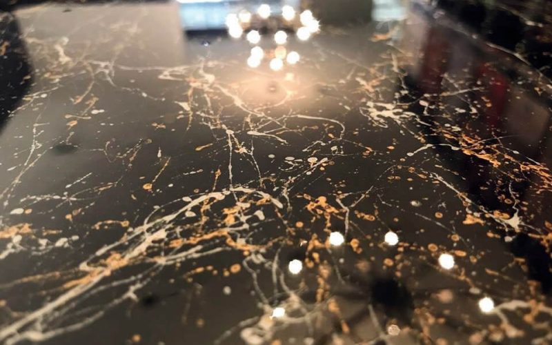 Black marble surface with white and gold veins.