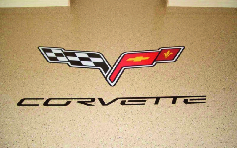 Corvette logo on speckled garage floor.
